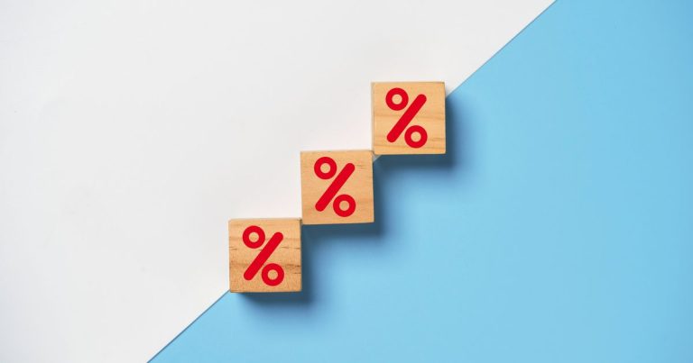 Wooden blocks with red percent signs arranged in an ascending staircase, representing the Federal Reserve raising interest rates